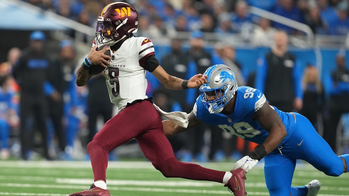 Jayden Daniels #5 of the Washington Commanders runs the ball against Za'Darius Smith #99 of the Detroit Lions during the fourth quarter in the NFC Divisional Playoff at Ford Field on January 18, 2025 in Detroit, Michigan.