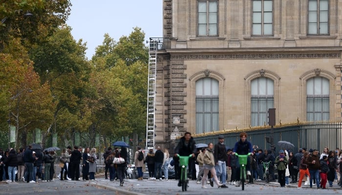 Police and forensic teams inspect a crane and a window believed to have been used in what the French Interior Ministry said was a robbery at the Louvre museum during which jewellery was stolen, as pedestrians pass nearby, in Paris, France, October 19, 2025. — Reuters