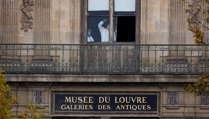 Police and forensic teams inspect a crane and a window believed to have been used in what the French Interior Ministry said was a robbery at the Louvre museum during which jewellery was stolen, as pedestrians pass nearby, in Paris, France, October 19, 2025. — Reuters